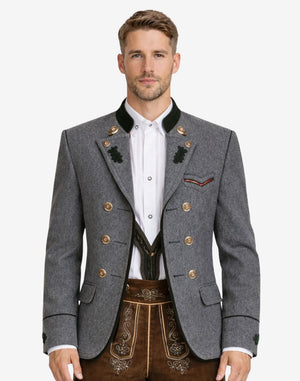 Model wearing alpine dark gray wool men’s Trachten jacket with traditional Bavarian design, double-breasted buttons, green collar accents, and classic Oktoberfest styling.