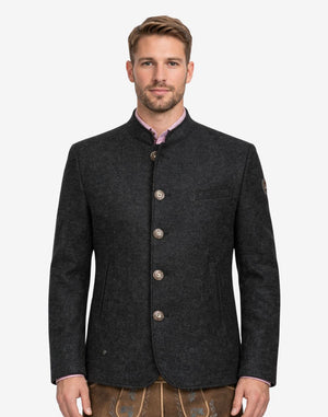 Model wearing deep rustic charcoal Trachten jacket for men with stand collar, traditional Bavarian style, button front, and paired with lederhosen for Oktoberfest outfit.