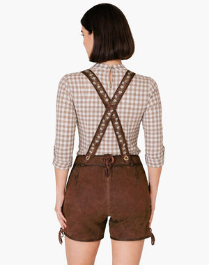 Person wearing a checkered shirt and brown leather suspenders with shorts on a white background