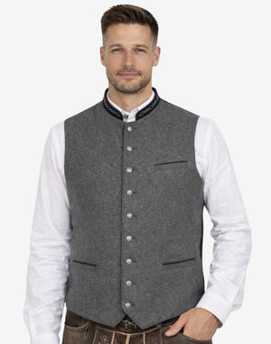 Model wearing grey German wool waistcoat with horn buttons, paired with traditional Bavarian outfit, ideal for Oktoberfest and Alpine wear.