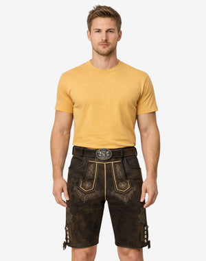 Model wearing authentic German lederhosen for men in dark brown leather with traditional Bavarian embroidery and belt