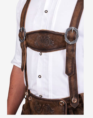 Close up of bundhosen suspenders displaying leather straps, metal buckles and embossed detailing in traditional Bavarian style