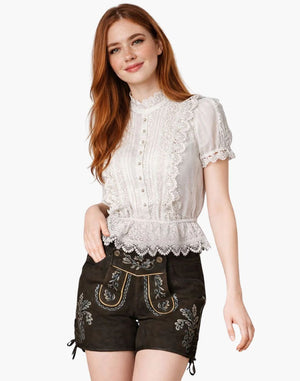 Woman wearing a white lace top and black embroidered shorts on a white background