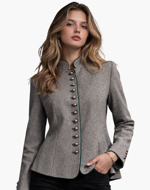 A young woman wearing a fitted grey wool jacket with decorative metal buttons down the front and green trim along the edges. The jacket has a structured, tailored shape, and she pairs it with black pants while standing against a plain light background.