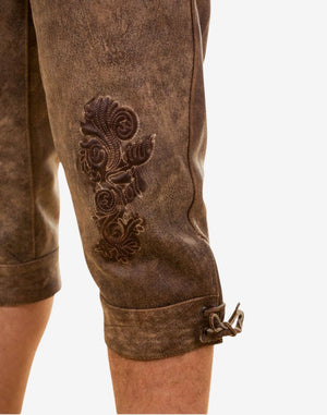 Close-up of men’s Oktoberfest bundhosen showing detailed leg embroidery, textured leather surface and traditional decorative stitching