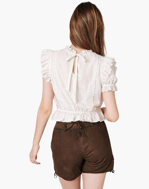 Woman wearing a white blouse with ruffled sleeves and brown shorts on a white background
