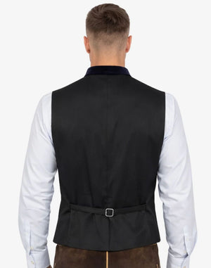 Man wearing a black vest over a white shirt on a white background