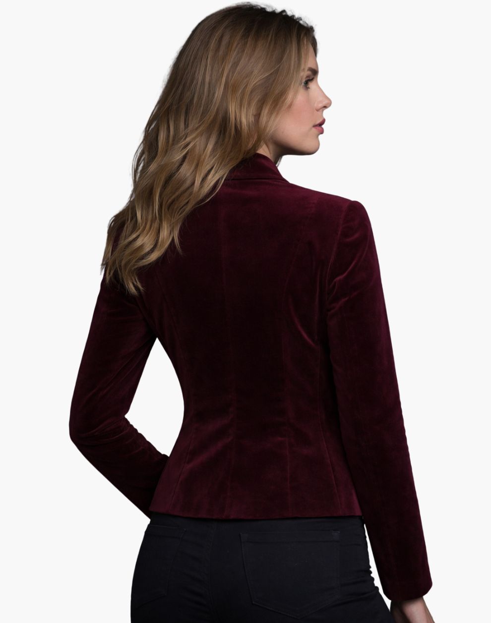 Rear view of a woman wearing a burgundy velvet fitted jacket with a structured silhouette, paired with dark jeans.