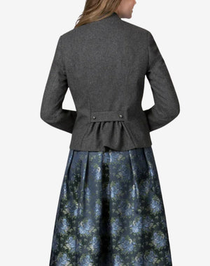 Back view of a women’s charcoal grey Bavarian-style trachten jacket with a fitted waist, decorative back pleats, and traditional Alpine tailoring worn over a floral dirndl skirt.