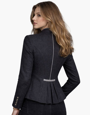 Back view of a woman wearing a traditional women’s Trachten blazer in charcoal grey with contrast piping and pleated back detail, against a white background.
