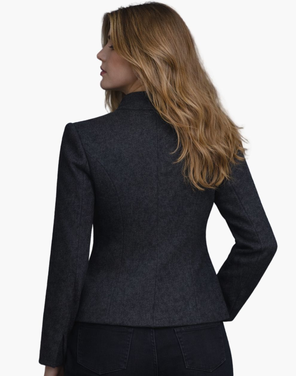 Back view of a woman wearing the same dark charcoal fitted jacket, showing contoured seam lines and a gently flared hem over dark jeans. Her shoulder-length blonde hair falls loosely over the collar. The background is plain light gray, creating a simple studio look.