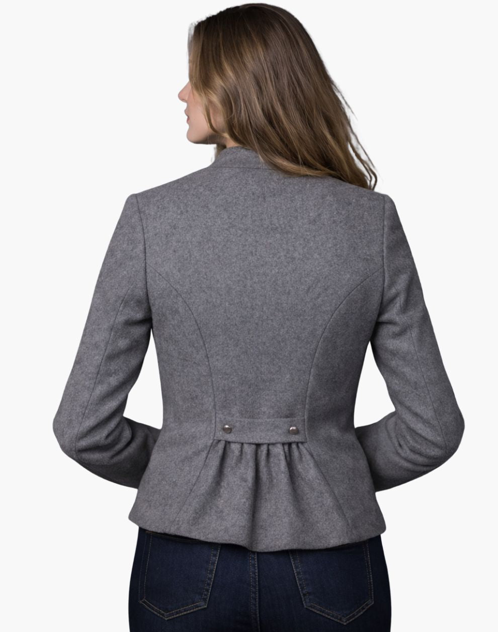 Back view of a woman wearing a light grey tailored Trachten jacket with a fitted waist and pleated back detail, paired with dark jeans, against a white background.