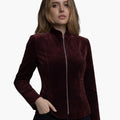 Female model wearing a burgundy velvet jacket with a high collar and front zipper, featuring a fitted tailored silhouette.