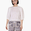 Woman wearing a white lace top and denim shorts on a white background