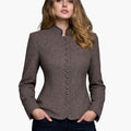 Woman wearing an authentic Bavarian Trachten jacket in brown with decorative buttons, a high collar, and a fitted traditional design, paired with dark jeans, against a white background.