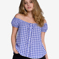 Front view of a woman wearing a blue and white gingham off-shoulder dirndl blouse with short puff sleeves, ruffle trim, and button-down front, paired with black shorts.