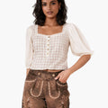 Woman wearing a white blouse with ruffled sleeves and brown embroidered shorts on a white background