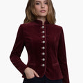 Woman wearing a burgundy velvet jacket with silver buttons on a white background