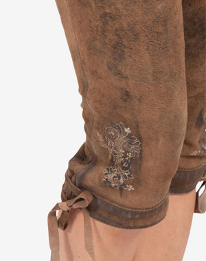 Close-up of brown leather bundhosen knee area showing traditional Bavarian embroidery, vintage suede texture, and adjustable lace-up tie at the hem.