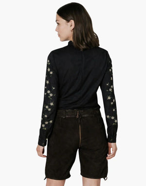 Woman wearing a black long-sleeve top with floral patterns and black shorts on a white background