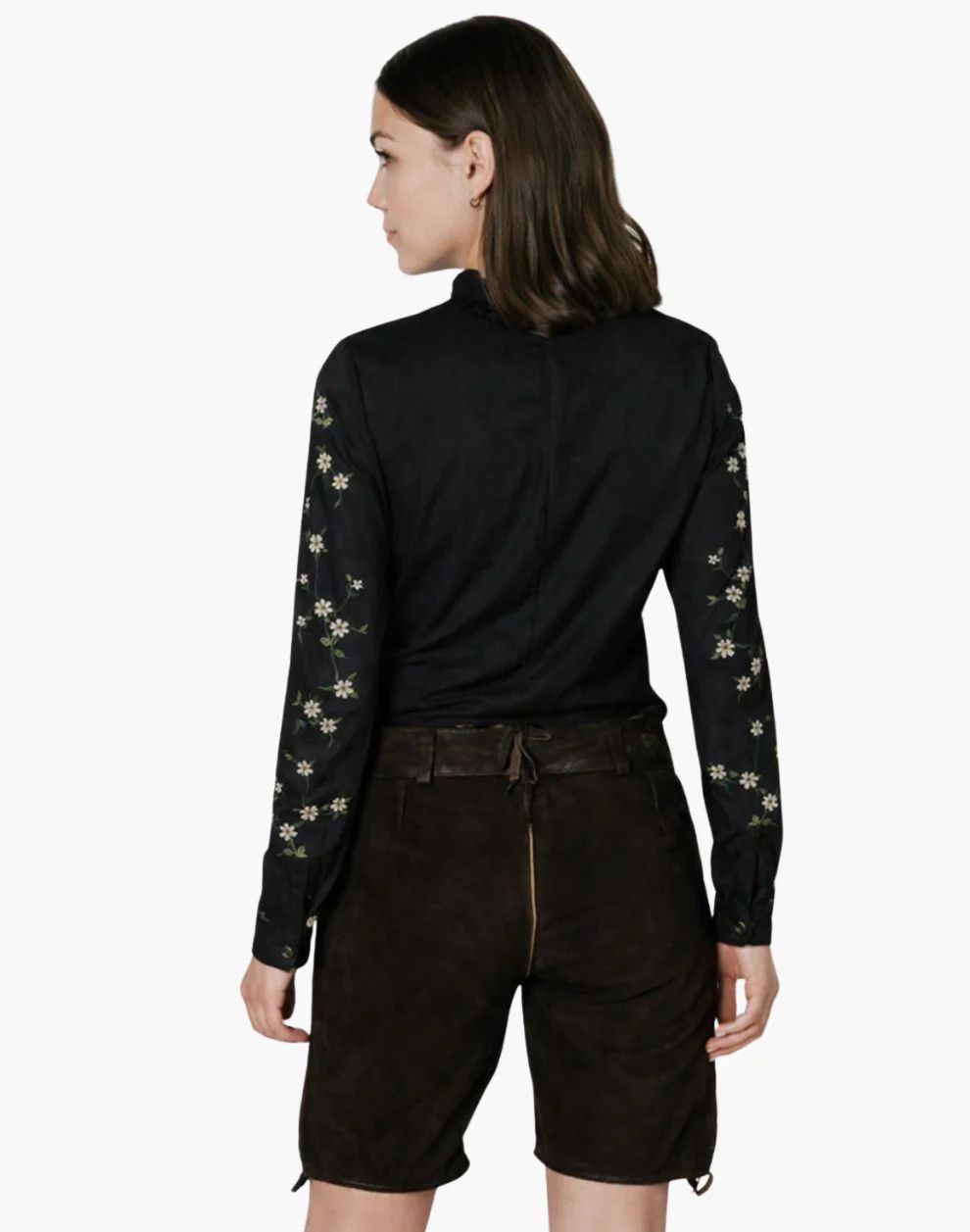 Woman wearing a black long-sleeve top with floral patterns and black shorts on a white background