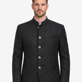 Model wearing deep rustic charcoal Trachten jacket for men with stand collar, traditional Bavarian style, button front, and paired with lederhosen for Oktoberfest outfit.