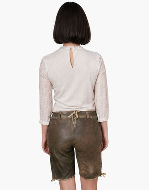 Person wearing a white lace top and brown leather shorts on a white background