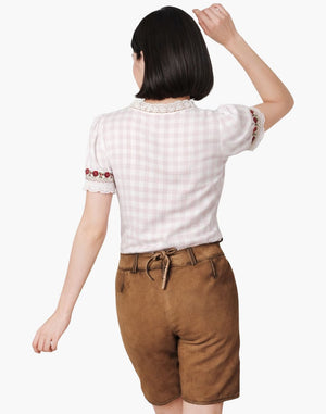Woman wearing a white checkered shirt with embroidered details and brown shorts on a white background