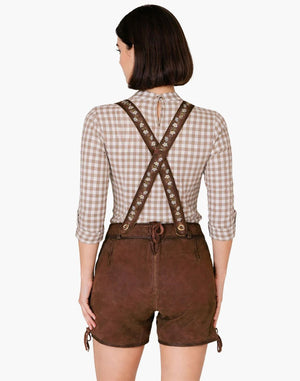 Person wearing a checkered shirt and brown leather suspenders with shorts on a white background