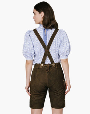Back view of a woman wearing brown embroidered lederhosen shorts with suspender and a blue  shirt in traditional Oktoberfest style.