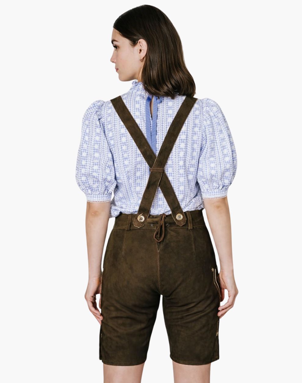 Back view of a woman wearing brown embroidered lederhosen shorts with suspender and a blue  shirt in traditional Oktoberfest style.