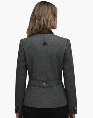 Back view of a woman wearing a fitted charcoal gray wool jacket with structured seams and a gently flared peplum-style hem. The jacket features a decorative back tab with two buttons at the waist and subtle gathering below it. She pairs it with dark jeans, and her shoulder-length blonde hair falls over the collar. The background is plain light gray in a studio setting.