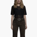 Woman wearing a black sheer top and brown shorts on a white background