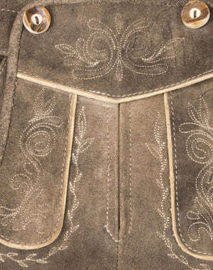 Close-up of women’s taupe suede lederhosen front panel featuring traditional floral embroidery, decorative stitching, and button detail in a vintage Bavarian style.