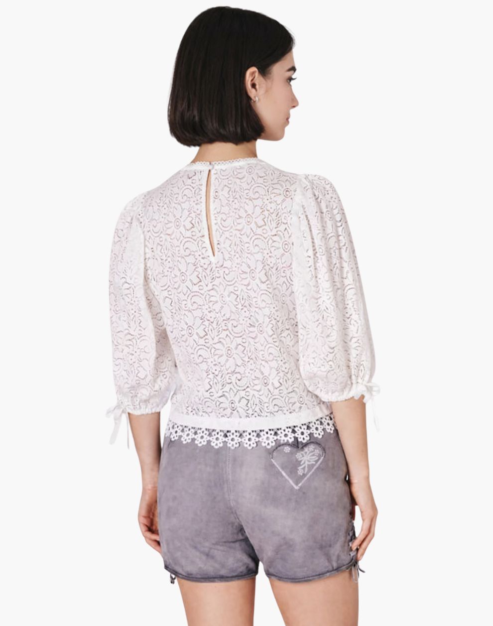 Woman wearing a white lace top and gray shorts on a white background