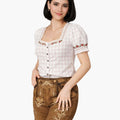 Woman wearing a traditional outfit with a white top and brown pants on a white background