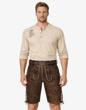 Front view of model wearing Men Festday Classic Lederhosen in brown leather with Bavarian embroidery and traditional belt buckle