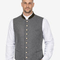 Model wearing mens authentic Alpine vest with grey wool fabric paired with traditional shirt and lederhosen.
