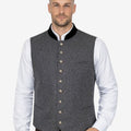 Model wearing mens gray wool Trachten vest paired with traditional shirt and lederhosen for classic Bavarian Oktoberfest outfit.