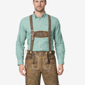 Model wearing traditional Alpine lederhosen for men with suspenders, brown leather Bavarian Oktoberfest outfit
