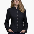 Woman wearing a charcoal grey Trachten-style jacket with decorative buttons, high collar, and a fitted tailored design, paired with dark jeans, against a white background.