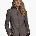 Woman wearing a premium brown tailored blazer with decorative buttons, a high collar, and a fitted structured design, against a white background.