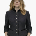 Woman wearing a premium German Trachten jacket in dark grey with a high collar, pearl-style buttons, and tailored traditional Bavarian design, paired with brown lederhosen, against a white background.