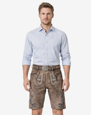 Model wearing premium mens Oktoberfest lederhosen in brown leather with Bavarian embroidery and traditional belt buckle for festival attire