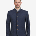 Model wearing rustic dark blue German heritage jacket for men with stand collar, traditional Trachten style, button front, and paired with lederhosen for Oktoberfest outfit.