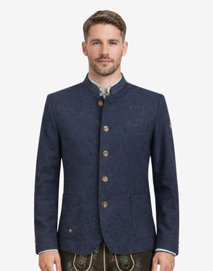 Model wearing rustic dark blue German heritage jacket for men with stand collar, traditional Trachten style, button front, and paired with lederhosen for Oktoberfest outfit.