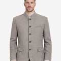 Model wearing rustic grey Bavarian jacket for men with traditional Trachten styling, stand collar, button front closure, tailored fit, and classic Oktoberfest outfit paired with lederhosen.