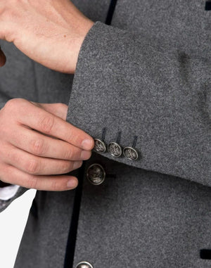 Close up detail of rustic wool Trachten jacket sleeve featuring decorative Bavarian metal buttons and premium wool texture.