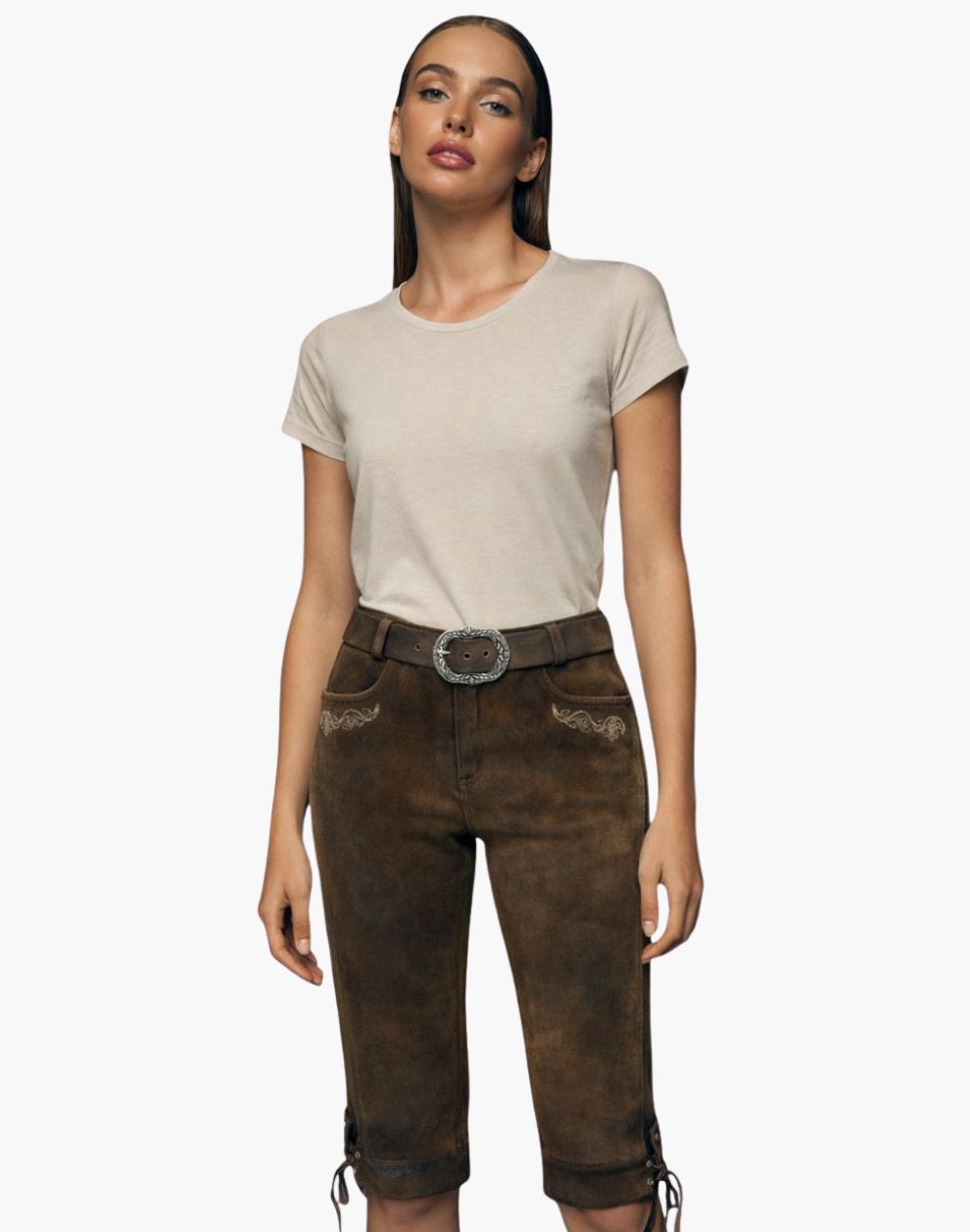 Woman wearing a beige t-shirt and brown Bundhosen with a belt on a white background