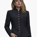 Front view of a woman wearing a charcoal grey tailored jacket with a stand-up collar and a vertical row of decorative gold-tone buttons down the front. The jacket features subtle welt pockets and a gently flared hem, paired with dark jeans. The background is plain light gray, giving the image a simple studio look.